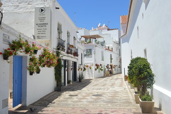 Gepflasterte Gasse durch weiße Häuser in Andalusien