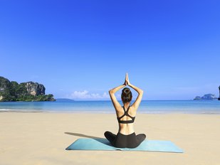 Eine Frau übt Yoga am Meer