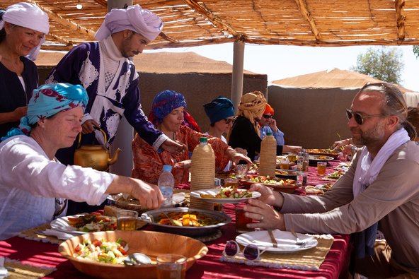 Gruppe von Menschen sitzen in der Wüste und essen