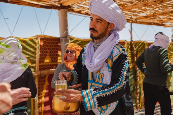 Ein Berber sitzt in Wüste Sahara im Hintergrund Gruppe von Menschen