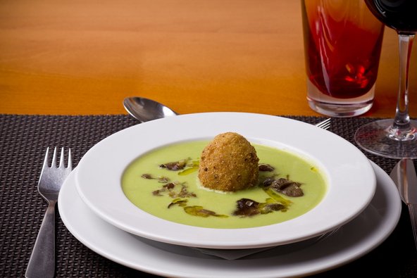 Eine grüne Suppe mit Kräutern und einem Bällchen