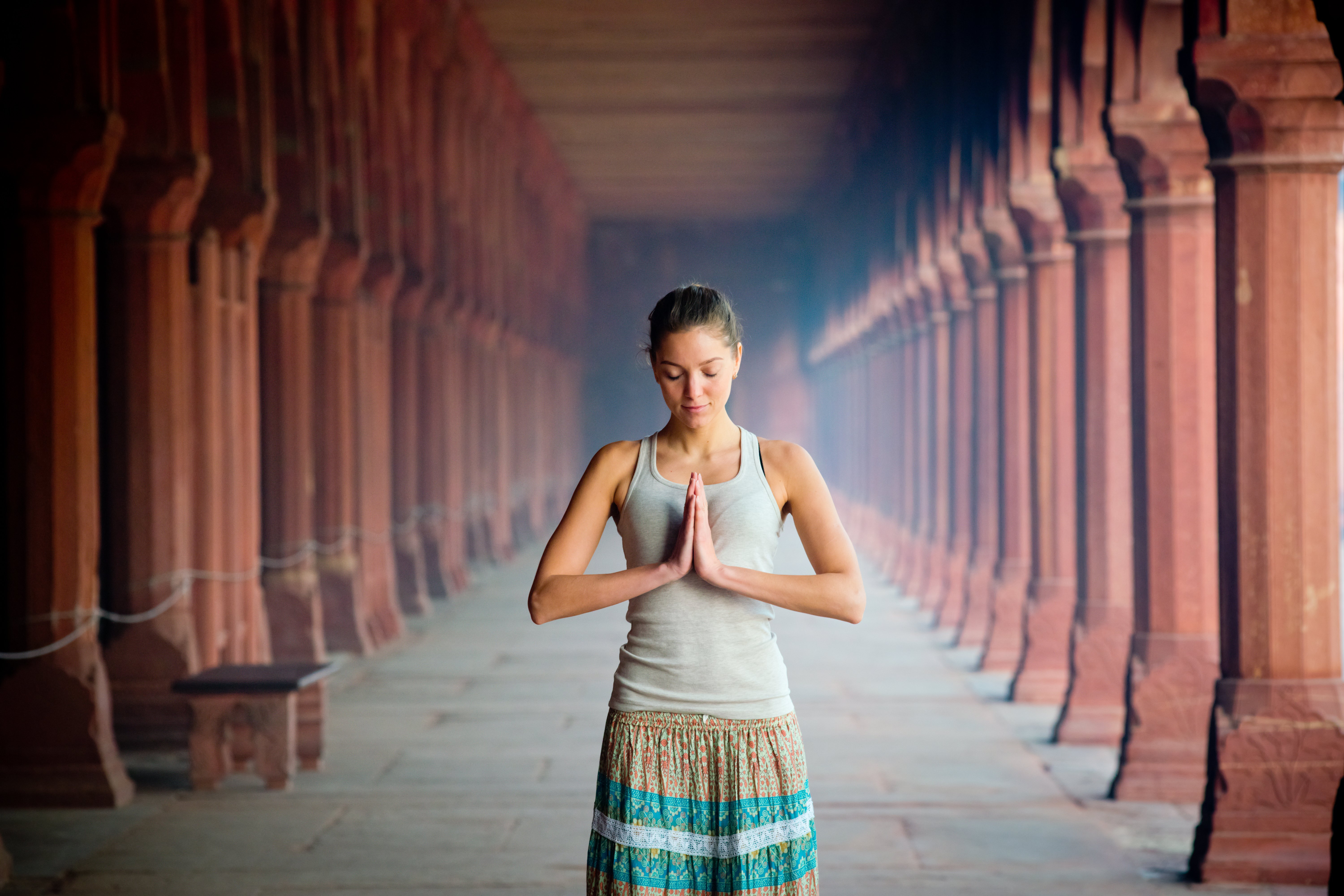 Eine junge Frau steht in einem Tempel die Hände im anjali mudra