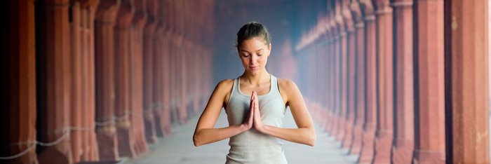 Eine junge Frau steht in einem Tempel die Hände im anjali mudra