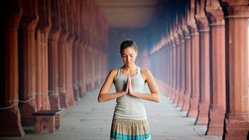 Eine junge Frau steht in einem Tempel die Hände im anjali mudra