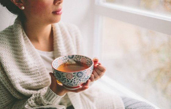 Frau mit einer Tasse Tee am Fenster