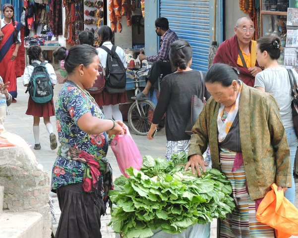 Eine Frau verkauft Gemüse auf einem Markt voller Menschen