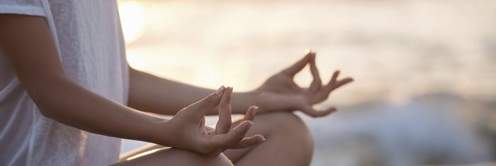 Ein junges Mädchen meditiert auf einem Felsen am Meer