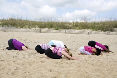 Eine Gruppe an Frauen befindet sind in der Haltung des Kindes am Strand