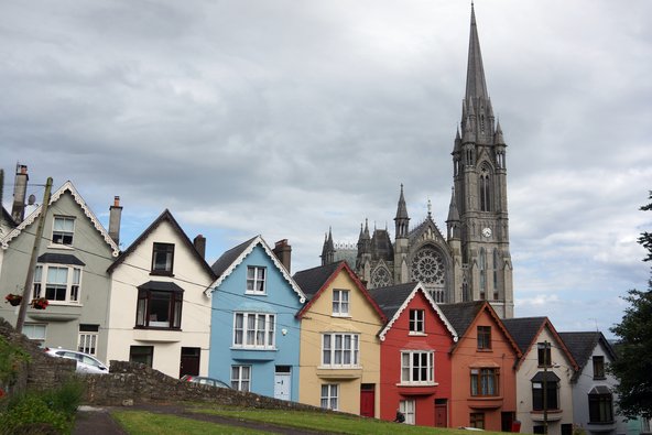 Aneinander gereihte verschiedenfarbige Häuser vor einer Kathedrale