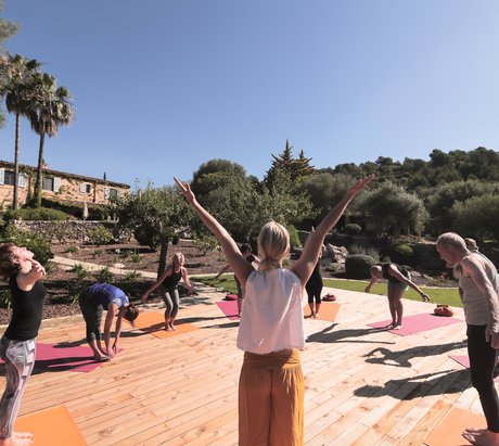 Eine Gruppe übt Yoga auf einer Terasse im Garten