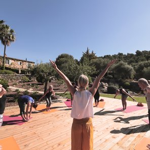 Eine Gruppe übt Yoga auf einer Terasse im Garten