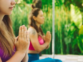 zwei Frauen im Schneidersitz und die Hände im Anjali Mudra