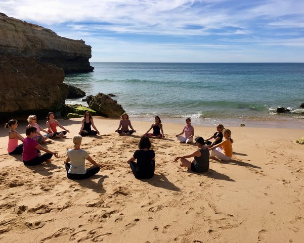 Frauen im Schneidersitz in einem Kreis am Strand