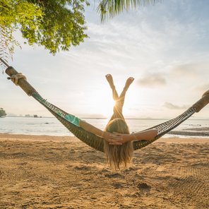 Eine junge Frau liegt auf einer Hängematte an einem tropischen Strand