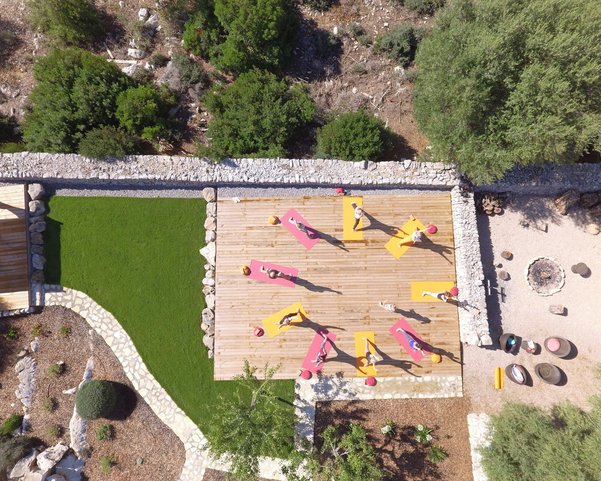 Eine Gruppe übt Yoga auf einer Terasse im Garten einer Finca
