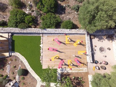 Eine Gruppe übt Yoga auf einer Terasse im Garten einer Finca