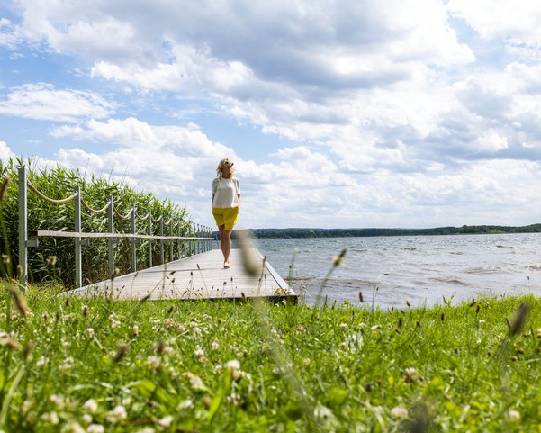 Frau auf dem Steg am See