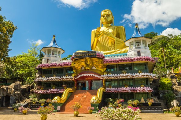 Goldene Buddha-Statue die auf einem bunten Tempel sitzt 