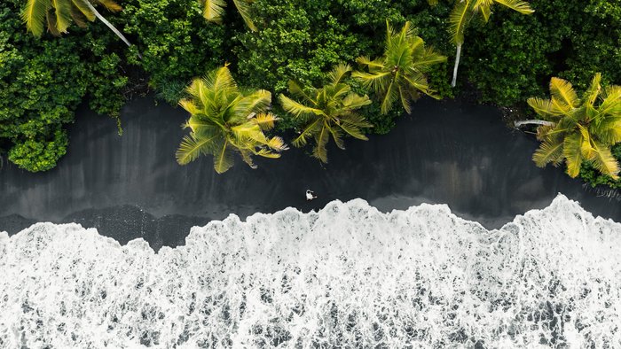 Schwarzer Strand mit Palmen auf Bali