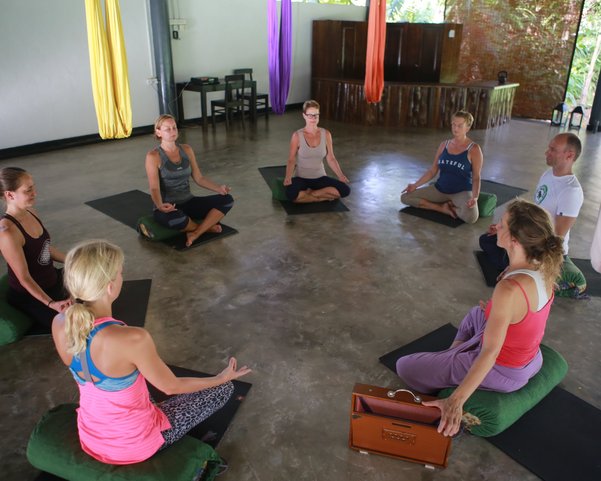 Yogis sitzen in einem Kreis in Meditationspose